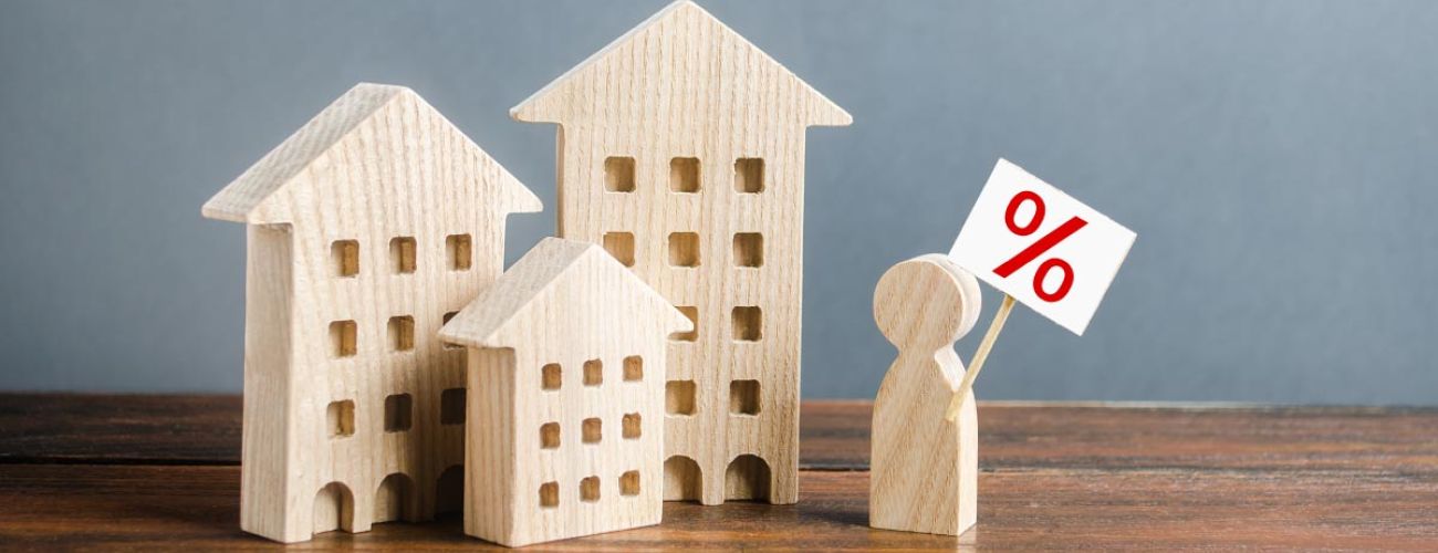 3 petites maisons en bois et un petit homme sur un bureau en bois