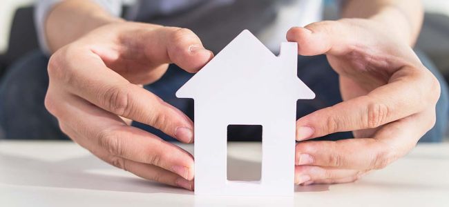 Photo zoom maquette maison d&eacute;coup&eacute; avec deux mains la tenant sur fond clair